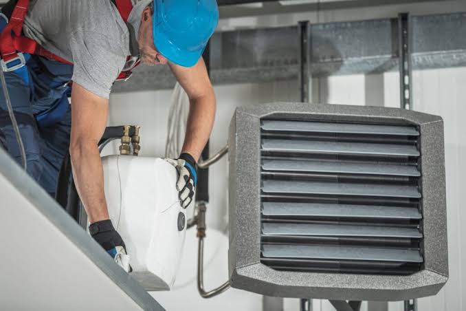 Technician servicing a residential air conditioning condenser